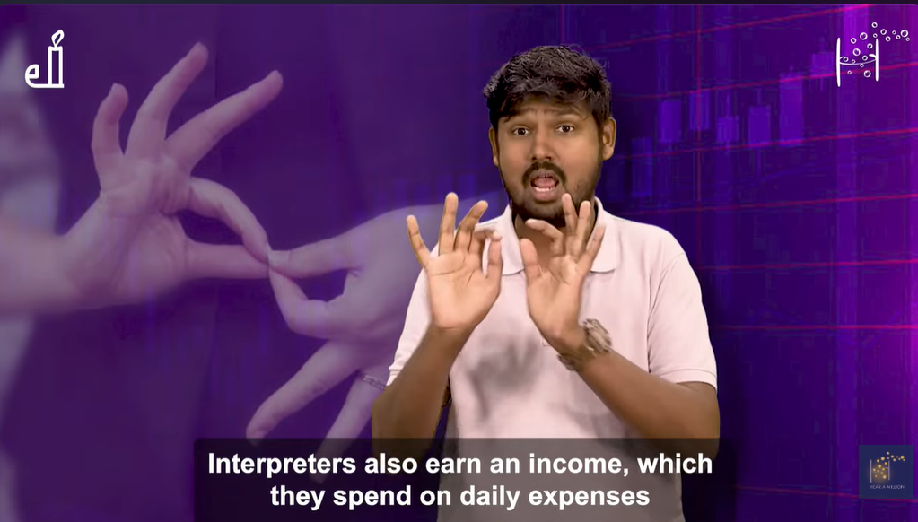 A presenter uses sign language in front of a purple background with a large hand gesture graphic