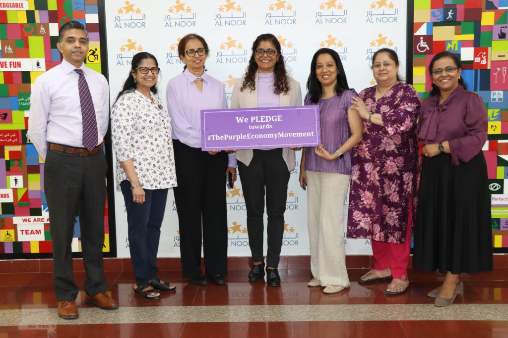 Group holding a Purple Economy pledge sign at an Al Noor event.