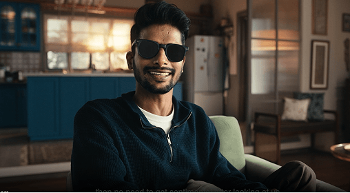 Man wearing sunglasses smiling while seated indoors.