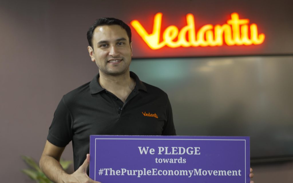 Person holding a Purple Economy pledge sign in a Vedantu office.