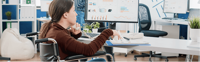 Person using a wheelchair working at a computer with accessible digital systems and analytics.