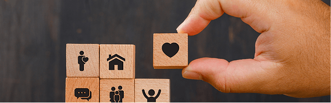 Hand placing a heart icon block beside inclusion symbols.
