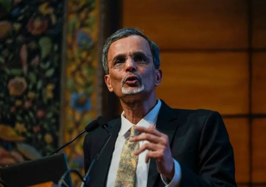 V. Anantha Nageswaran speaking at a podium during a conference, gesturing while delivering a presentation.